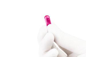 mano nel medico guanto Tenere plastica rosa colore biologico med capsula isolato su bianca sfondo avvicinamento foto