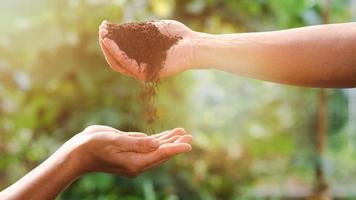 il agricoltori mano versato fertile suolo in il mani quello supportato il in basso, il concetto di abbondanza nel il suolo, preservare il ambiente, ecologico sviluppo, non tossico agricoltura foto