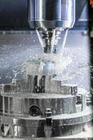 verticale foto di industriale bagnato fresatura processi nel 5 assi cnc macchina con refrigerante flusso sotto pressione e congelato spruzzi