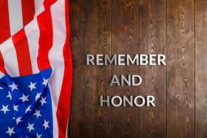 parole ricorda e onore di cui con argento metallo lettere su di legno sfondo con Stati Uniti d'America bandiera su il sinistra lato foto