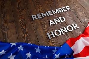 parole ricorda e onore di cui con argento metallo lettere su di legno sfondo con Stati Uniti d'America bandiera sotto foto