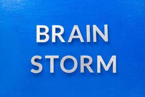 il frase cervello tempesta di cui con argento metallo lettere su blu tavola nel piatto posare con centrale composizione foto