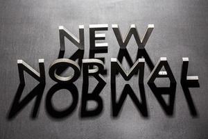 nuovo normale parola composto di argento metallo lettere su un' piatto opaco nero superficie con ombre retroilluminato foto