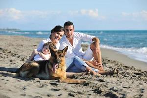 contento famiglia giocando con cane su spiaggia foto