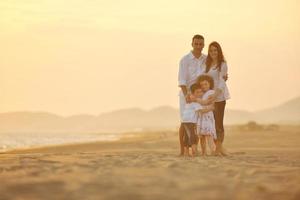 contento giovane famiglia avere divertimento su spiaggia a tramonto foto