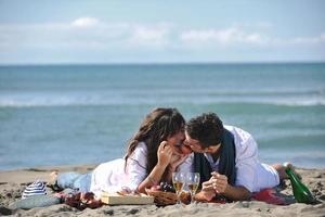 giovane coppia godendo picnic su il spiaggia foto