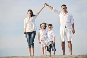 famiglia su spiaggia mostrando casa cartello foto