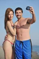 contento giovane coppia nel amore assunzione fotografie su spiaggia