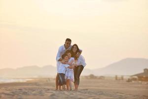 contento giovane famiglia avere divertimento su spiaggia a tramonto foto