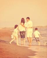 contento giovane famiglia avere divertimento su spiaggia a tramonto foto