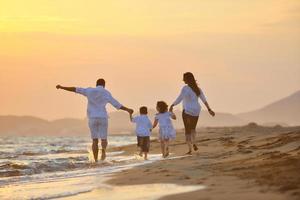 contento giovane famiglia avere divertimento su spiaggia a tramonto foto