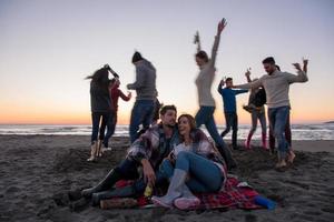 coppia godendo con amici a tramonto su il spiaggia foto