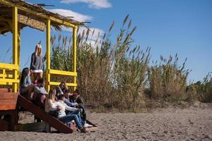 gruppo di amici avendo divertimento su autunno giorno a spiaggia foto