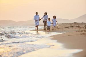 contento giovane famiglia avere divertimento su spiaggia a tramonto foto