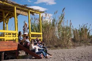 gruppo di amici avendo divertimento su autunno giorno a spiaggia foto