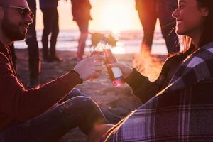 coppia godendo con amici a tramonto su il spiaggia foto