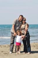 contento giovane famiglia avere divertimento su spiaggia foto