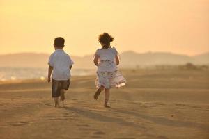 contento giovane famiglia avere divertimento su spiaggia a tramonto foto