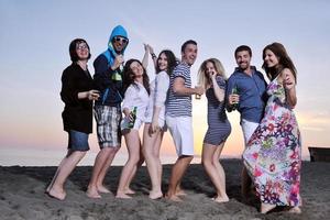 gruppo di giovane persone godere estate festa a il spiaggia foto