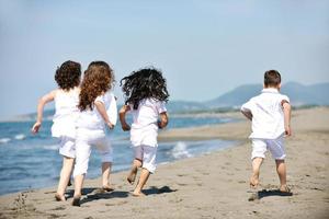 gruppo di bambini felici che giocano sulla spiaggia foto