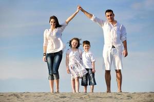 famiglia su spiaggia mostrando casa cartello foto