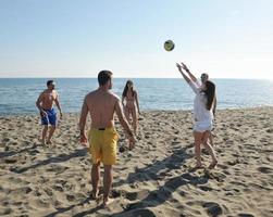 giovane persone gruppo avere divertimento e giocare spiaggia pallavolo foto