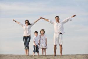 famiglia su spiaggia mostrando casa cartello foto