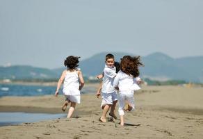 gruppo di bambini felici che giocano sulla spiaggia foto