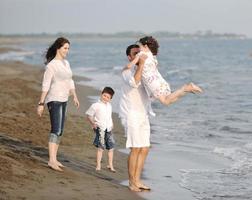 contento giovane famiglia avere divertimento su spiaggia foto