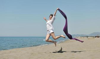 bellissimo giovane donna su spiaggia con sciarpa foto