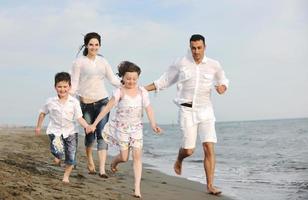 contento giovane famiglia avere divertimento su spiaggia foto