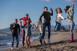 giovane amici salto insieme a autunno spiaggia foto