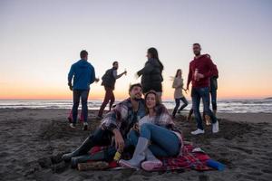 coppia godendo con amici a tramonto su il spiaggia foto