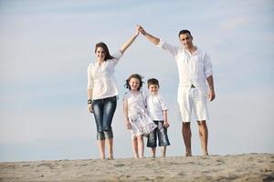 famiglia su spiaggia mostrando casa cartello foto