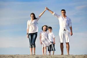 famiglia su spiaggia mostrando casa cartello foto