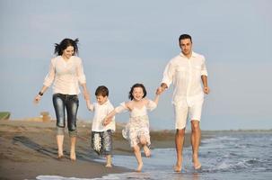 contento giovane famiglia avere divertimento su spiaggia a tramonto foto