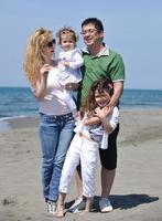 contento giovane famiglia avere divertimento su spiaggia foto