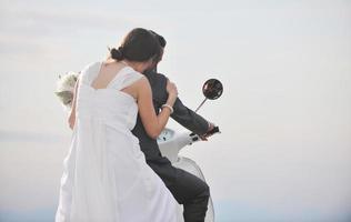 appena sposato coppia su il spiaggia cavalcata bianca scooter foto