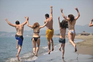 contento persone gruppo avere divertimento e in esecuzione su spiaggia foto