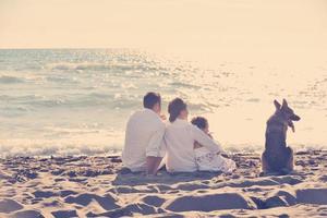 contento famiglia giocando con cane su spiaggia foto