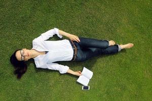 giovane donna che legge un libro nel parco foto