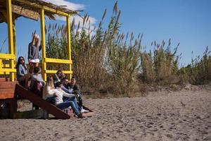 gruppo di amici avendo divertimento su autunno giorno a spiaggia foto