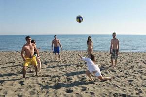 giovane persone gruppo avere divertimento e giocare spiaggia pallavolo foto