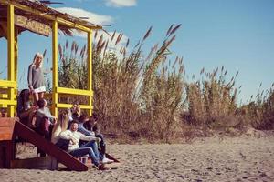 gruppo di amici avendo divertimento su autunno giorno a spiaggia foto