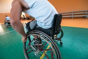 Disabilitato guerra veterani misto gara e età pallacanestro squadre nel sedie a rotelle giocando un' formazione incontro nel un' gli sport Palestra sala. portatori di handicap persone reinserimento e inclusione concetto foto