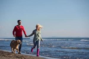 coppia con cane avendo divertimento su spiaggia su autunno giorno foto