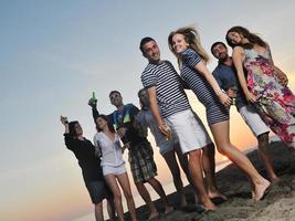 gruppo di giovane persone godere estate festa a il spiaggia foto