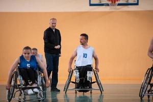 Disabilitato guerra veterani misto gara opporsi pallacanestro squadre nel sedie a rotelle fotografato nel azione mentre giocando un importante incontro nel un' moderno sala. foto