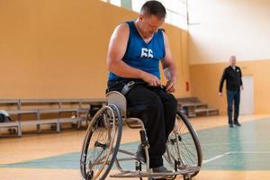 un' portatori di handicap pallacanestro giocatore prepara per un' incontro mentre seduta nel un' preparativi per sedie a rotelle per un' professionale pallacanestro incontro. il concetto di invalidità sport foto