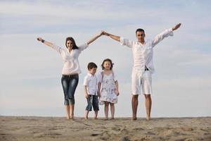 famiglia su spiaggia mostrando casa cartello foto